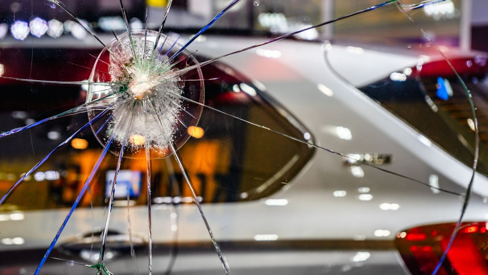 A man is installing a windshield on a car in a garage.