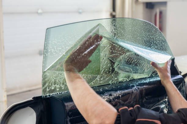 A person is applying window tinting to a car window.