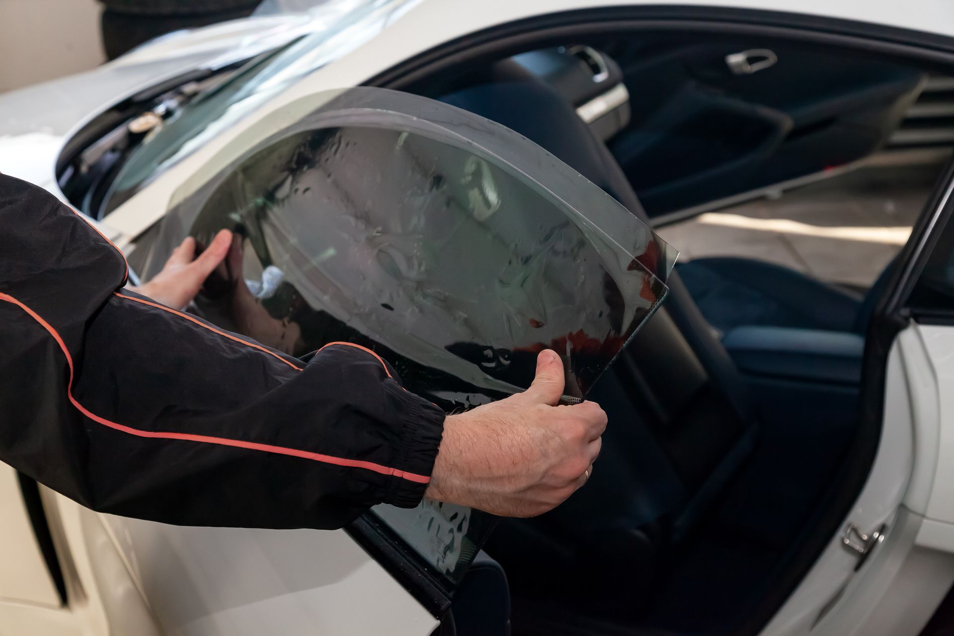 A man is applying tinted glass to a car window.