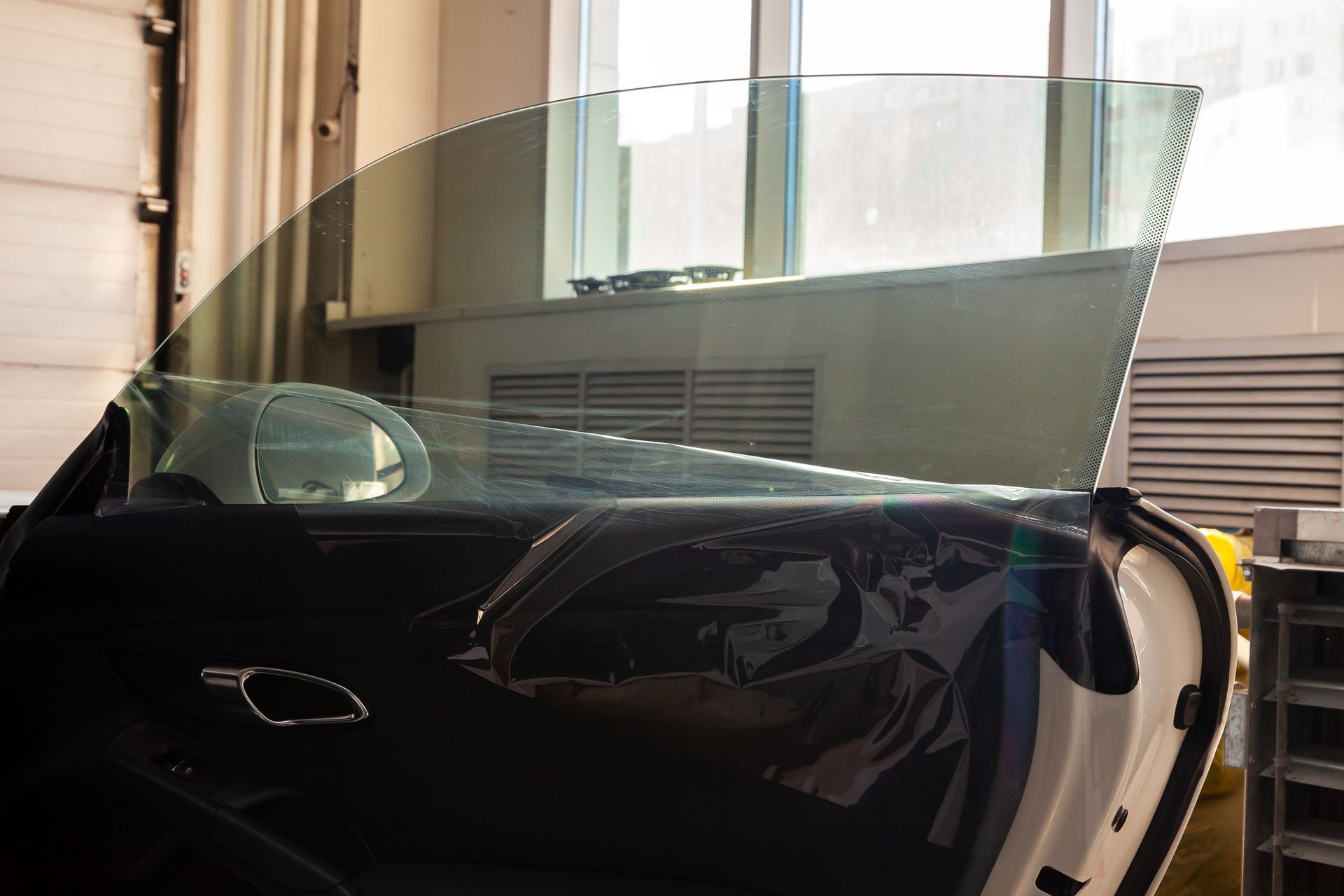 A car with a broken window is parked in a garage.