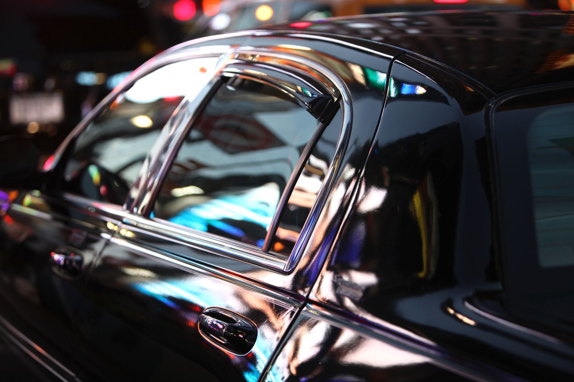 A black car is parked on the side of the road at night.