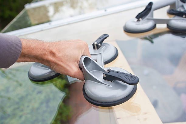 A person is using a suction cup to lift a glass window.