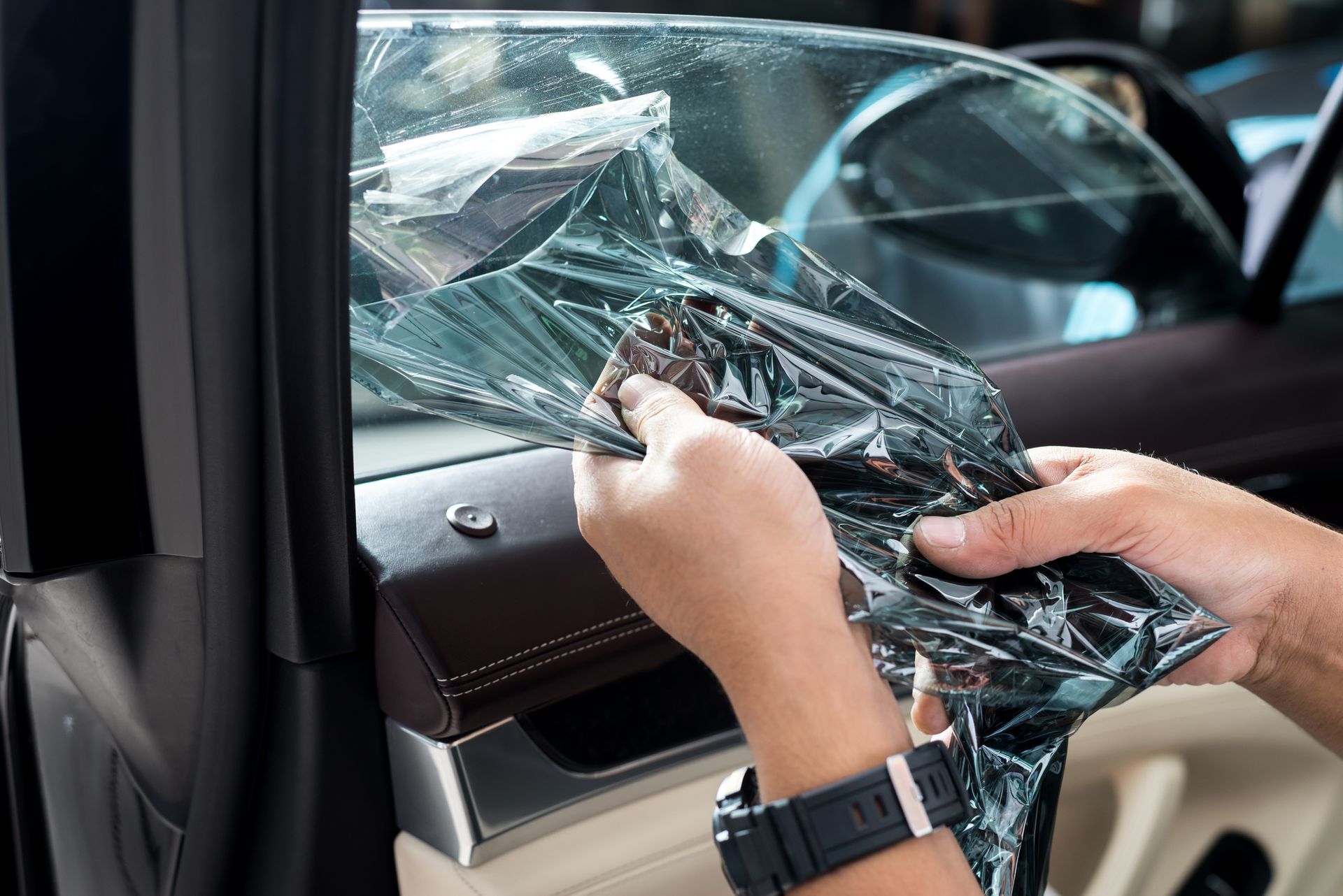 A person is applying window tinting to a car window.