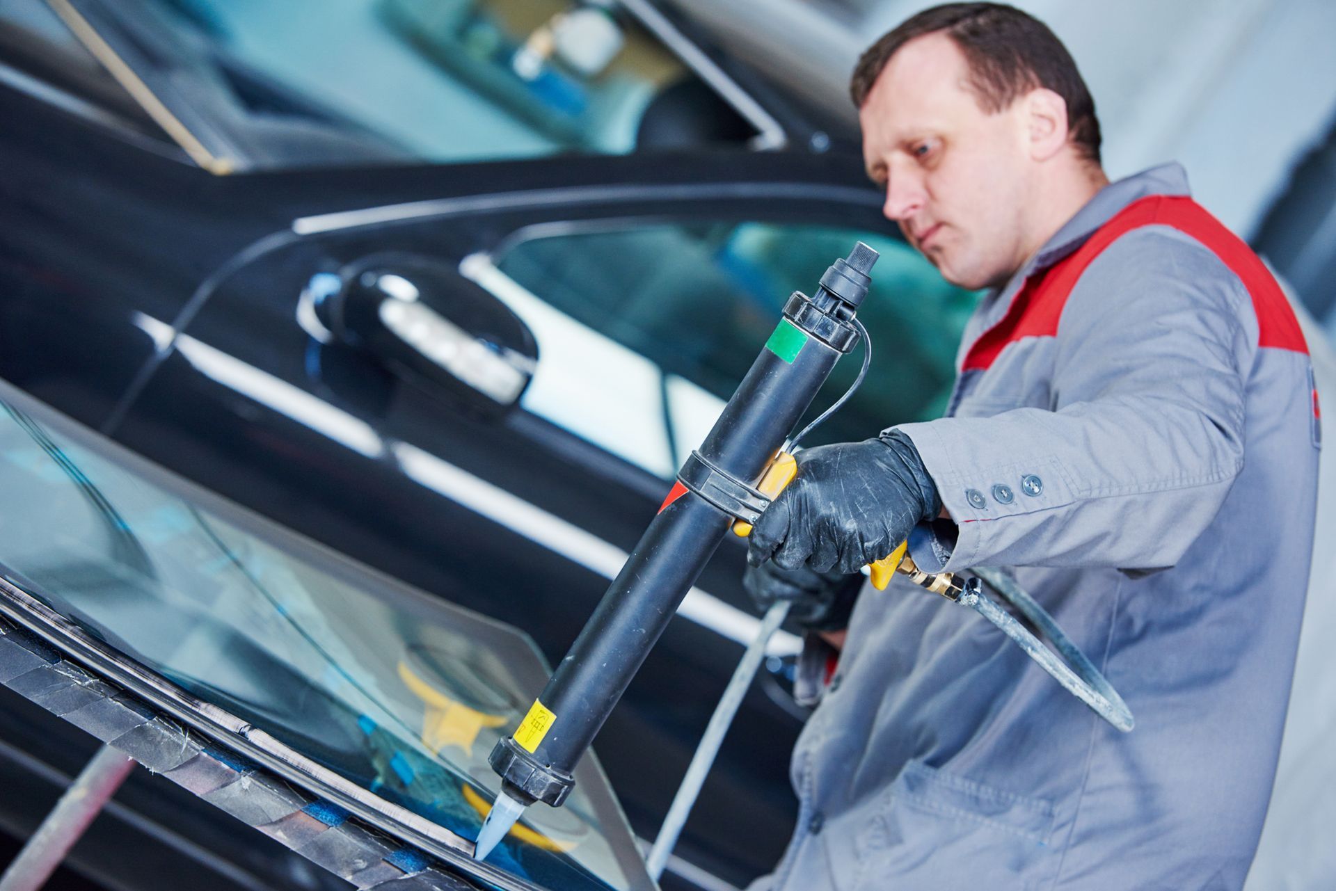 A man is working on a windshield of a car.