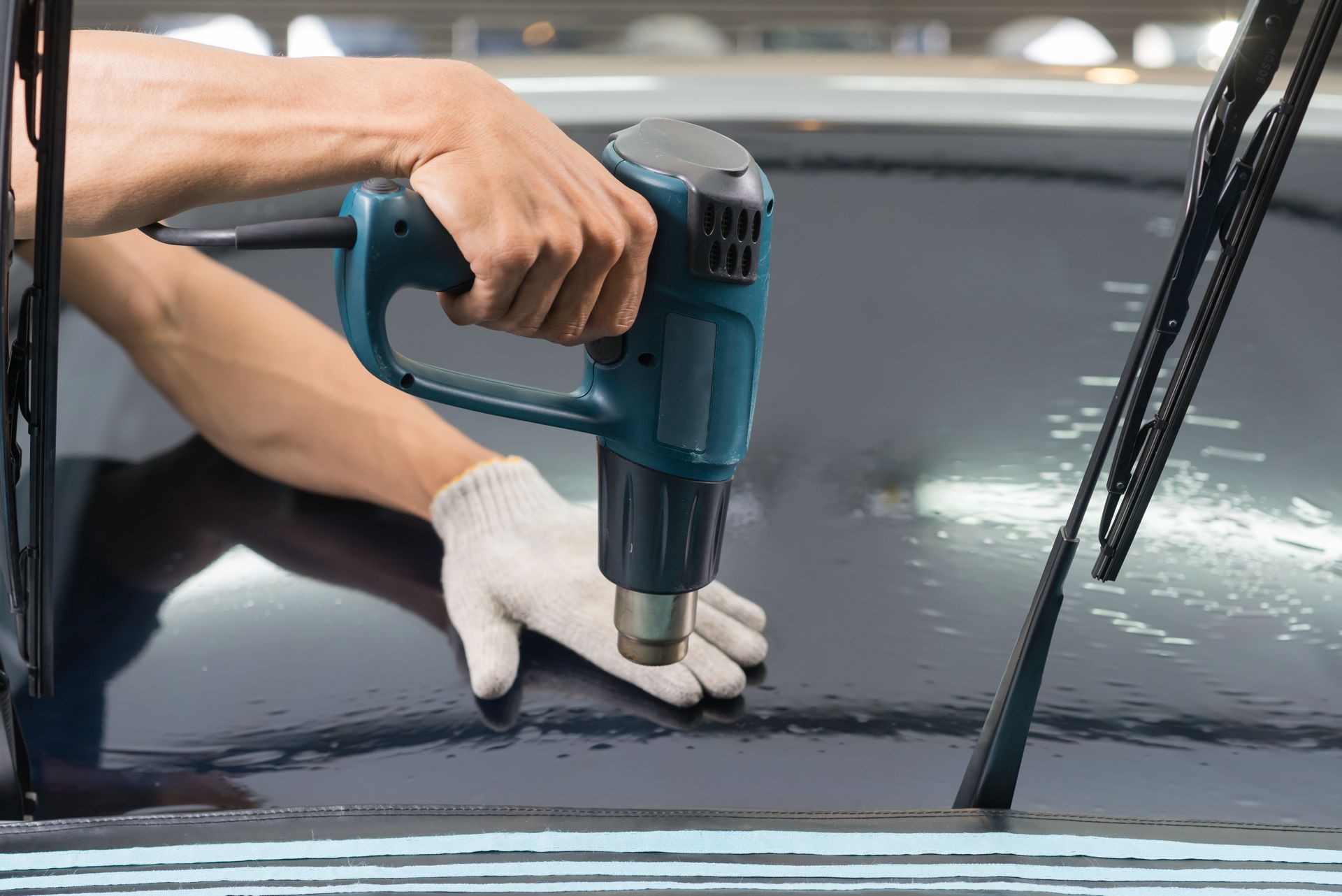 A person is applying tinted window film to a car windshield.