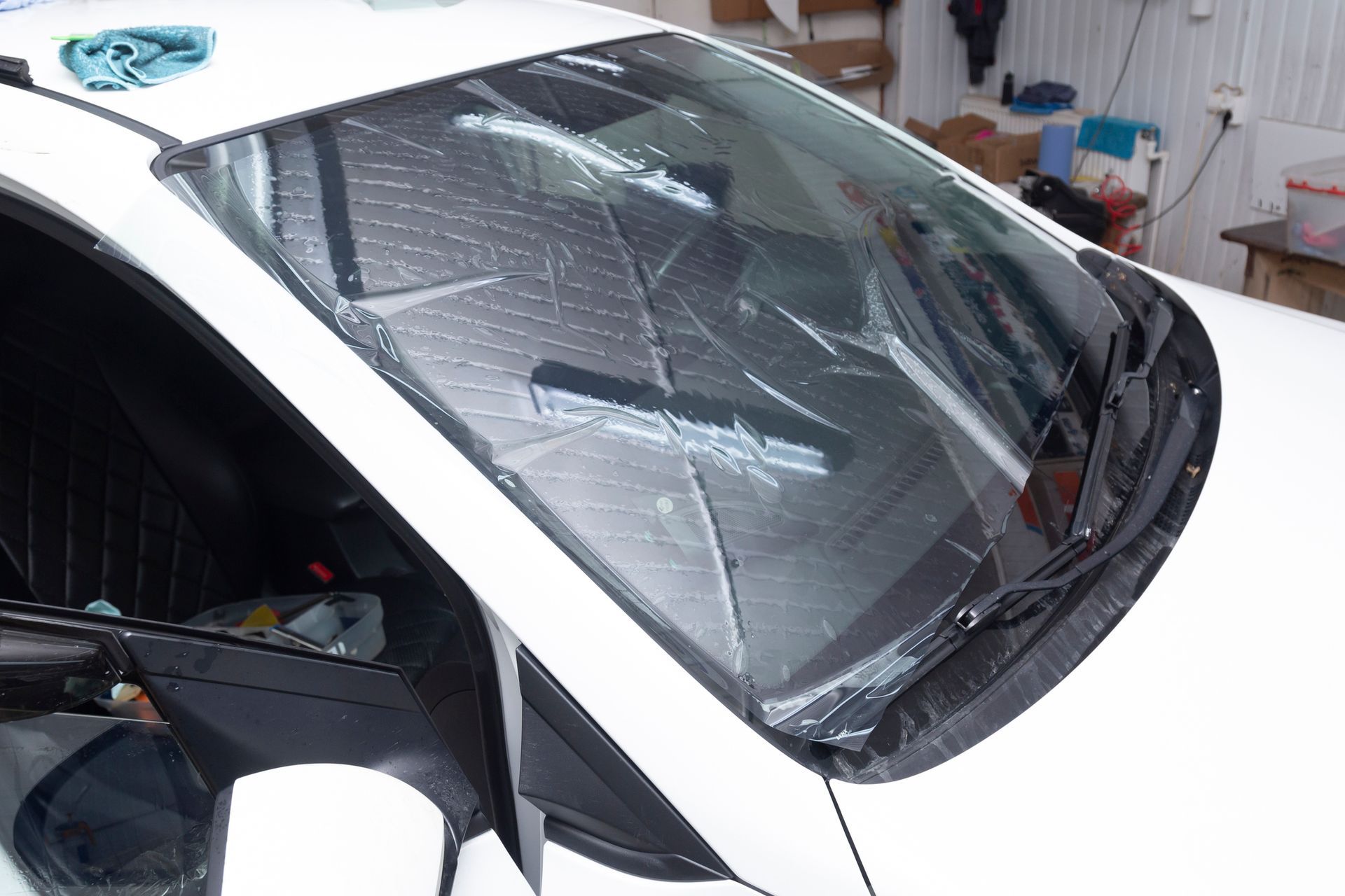 A white car with a broken windshield is sitting in a garage.