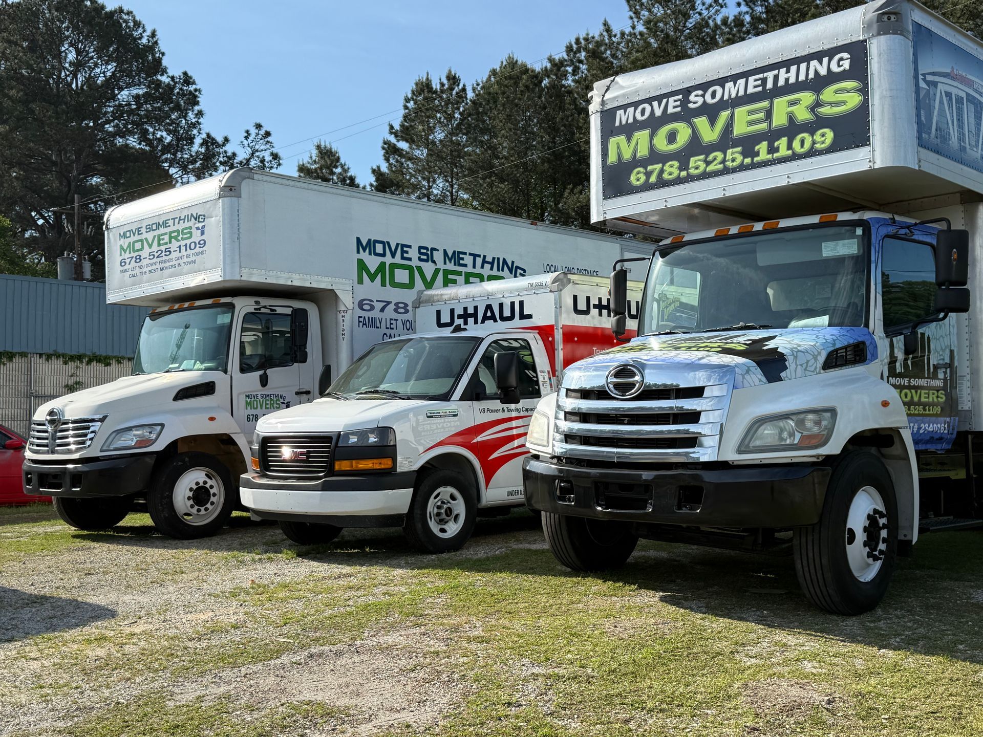Three moving trucks parked outside; one U-Haul and two trucks from 