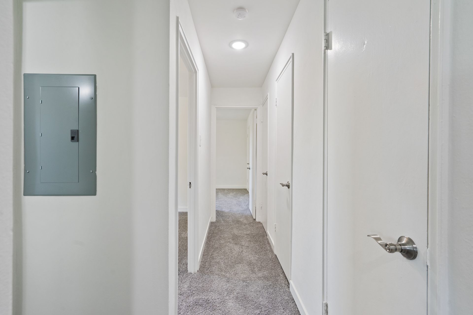 A long hallway with a carpeted floor and white walls in a house.