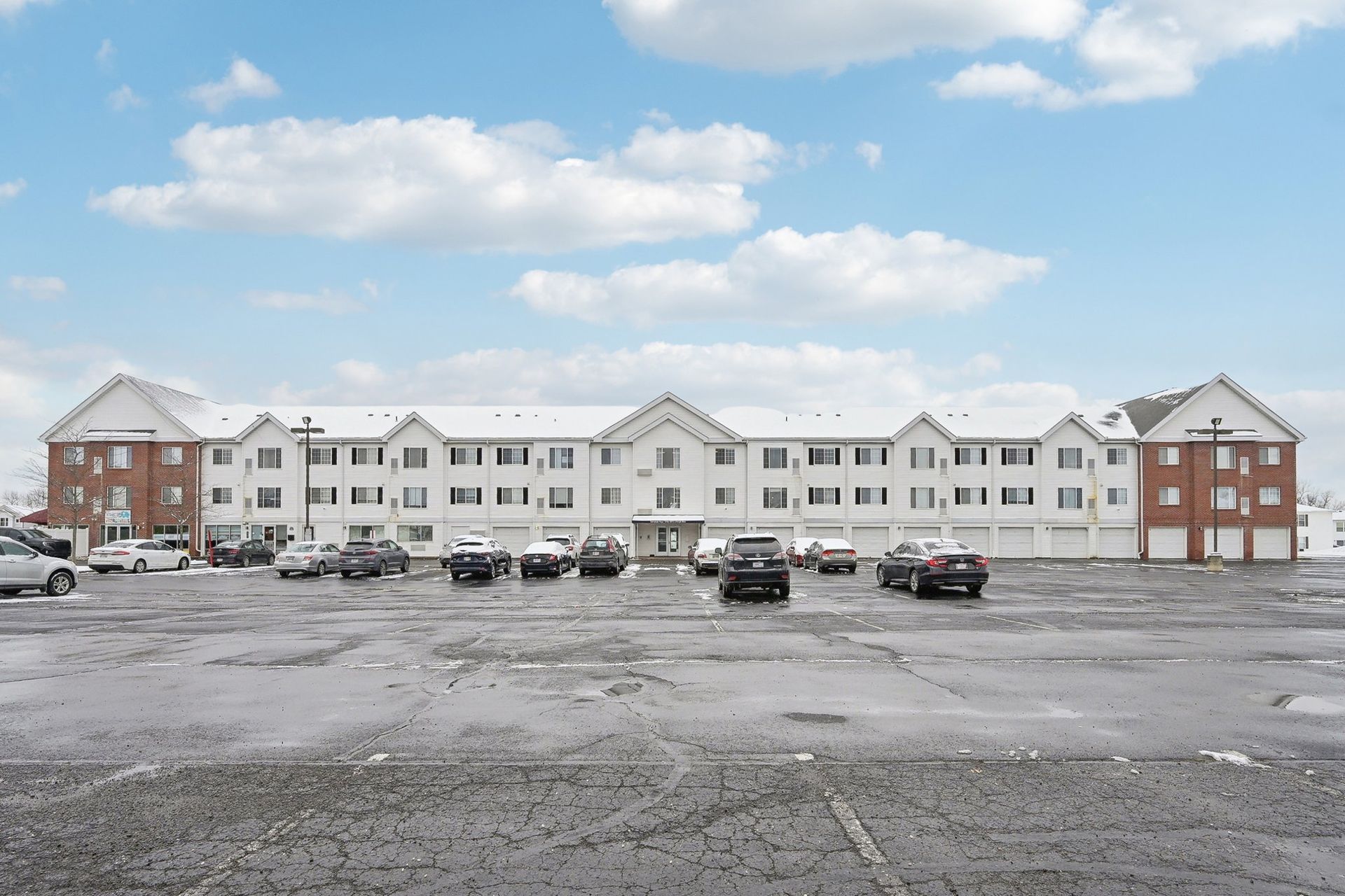 A large apartment building with a lot of cars parked in front of it.