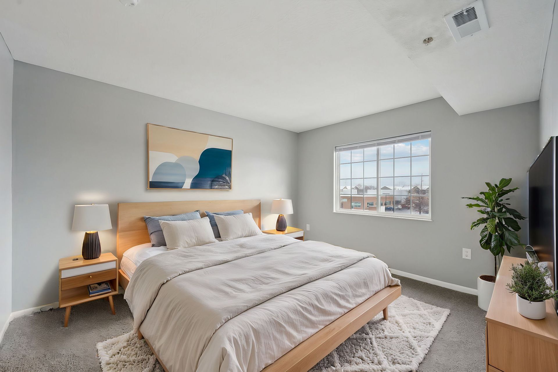 A bedroom with a large bed , dresser , nightstand and television.