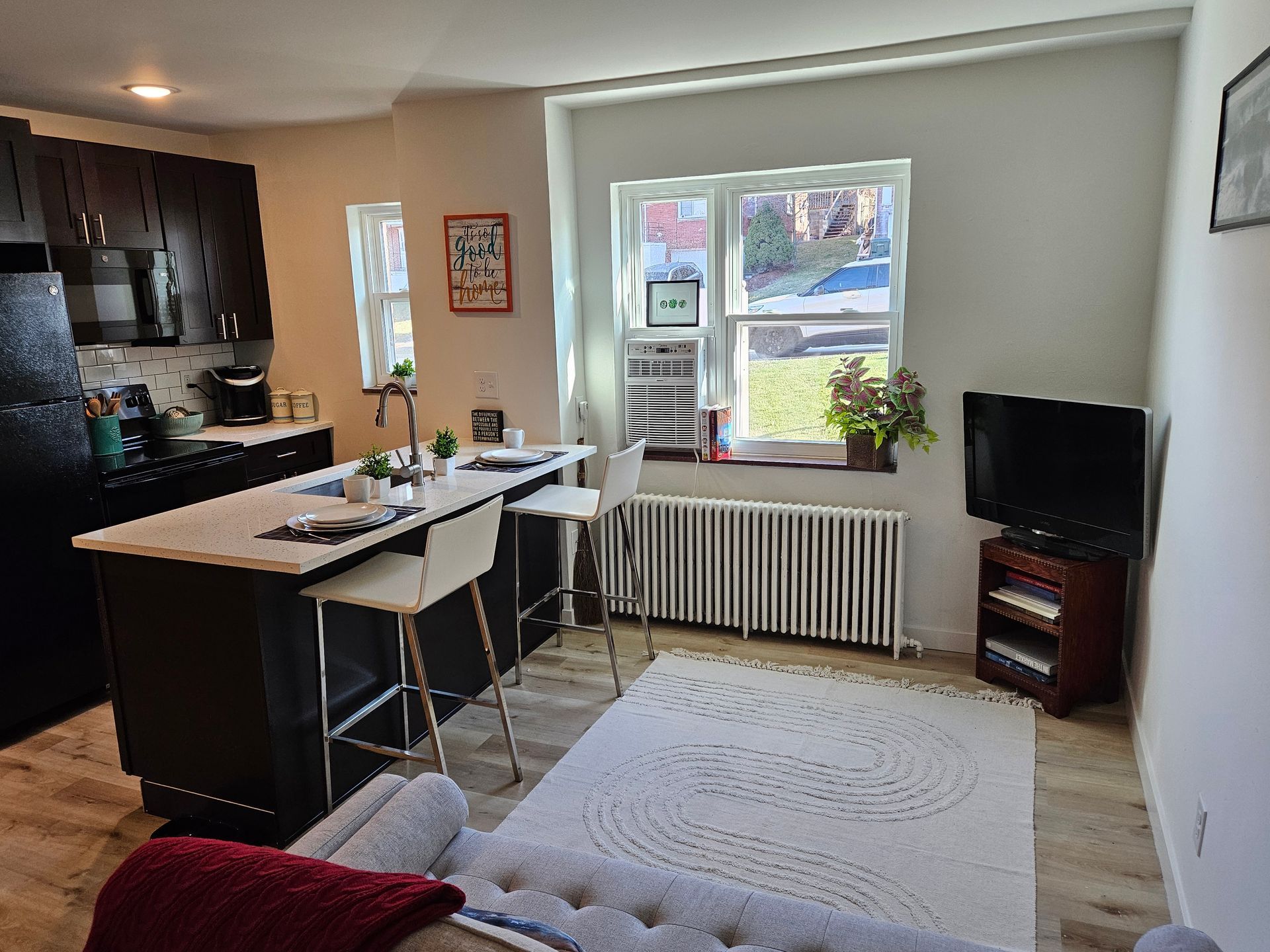 A living room with a couch , television , and kitchen.
