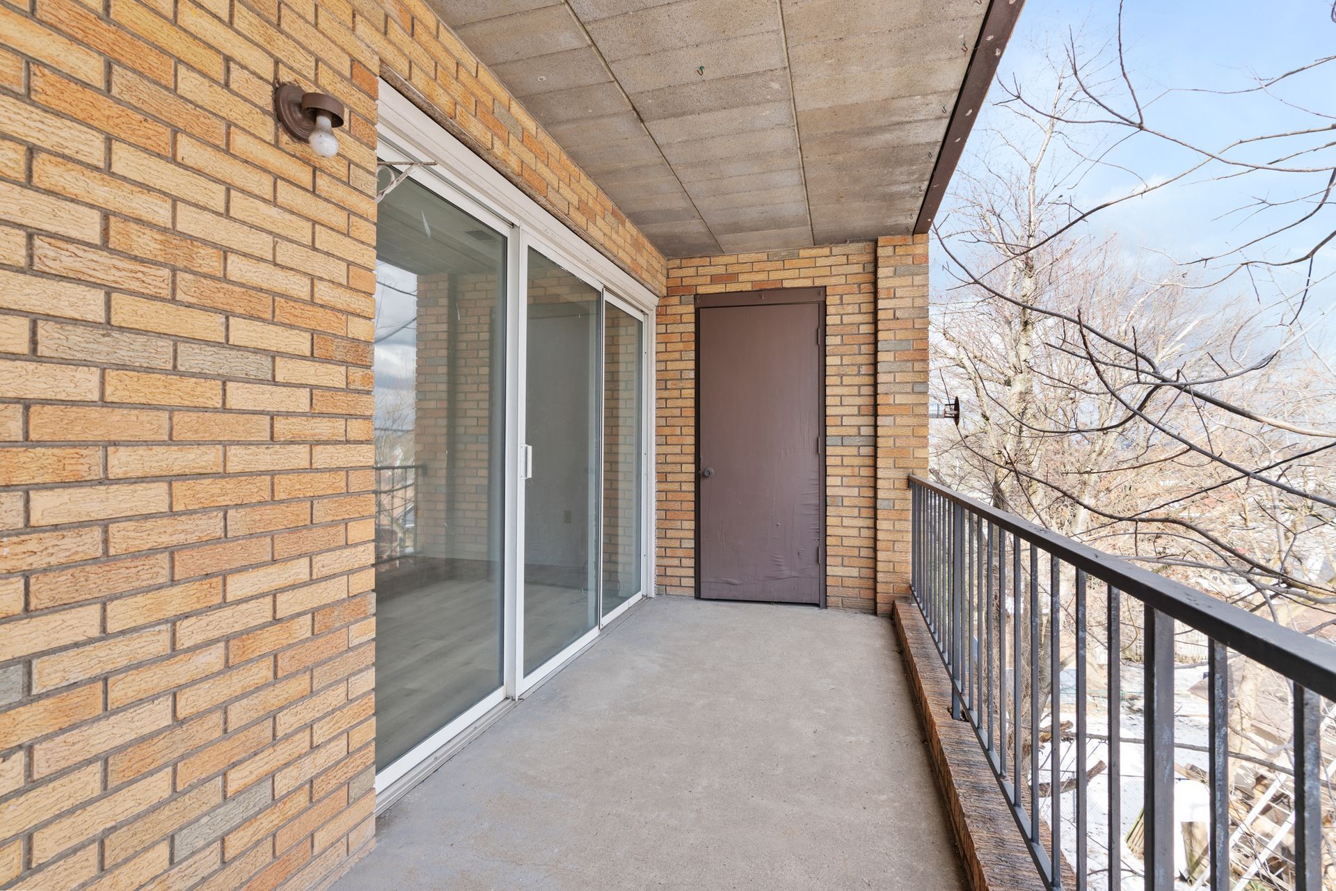 A balcony with a brick wall and sliding glass doors