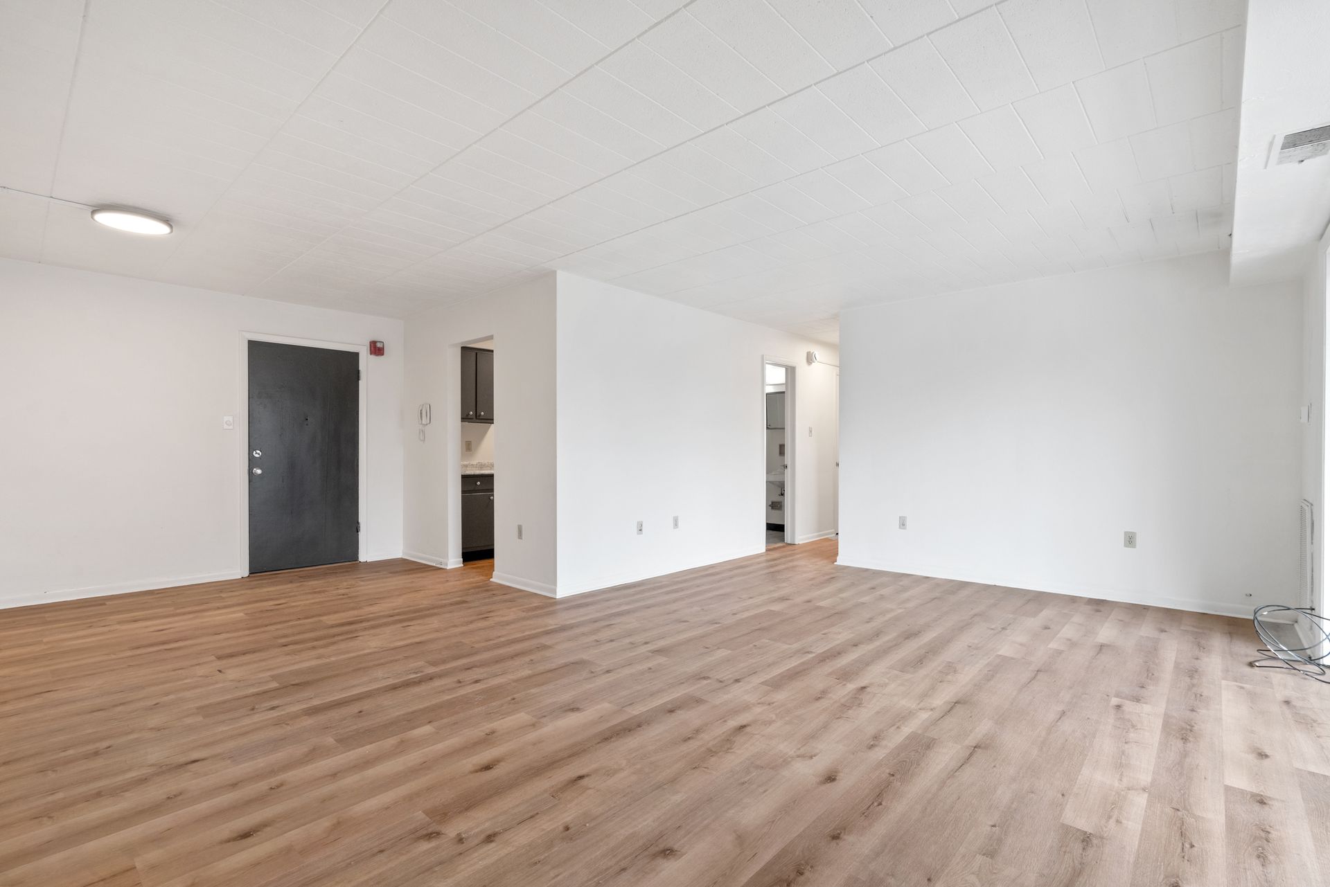 An empty living room with hardwood floors and white walls.