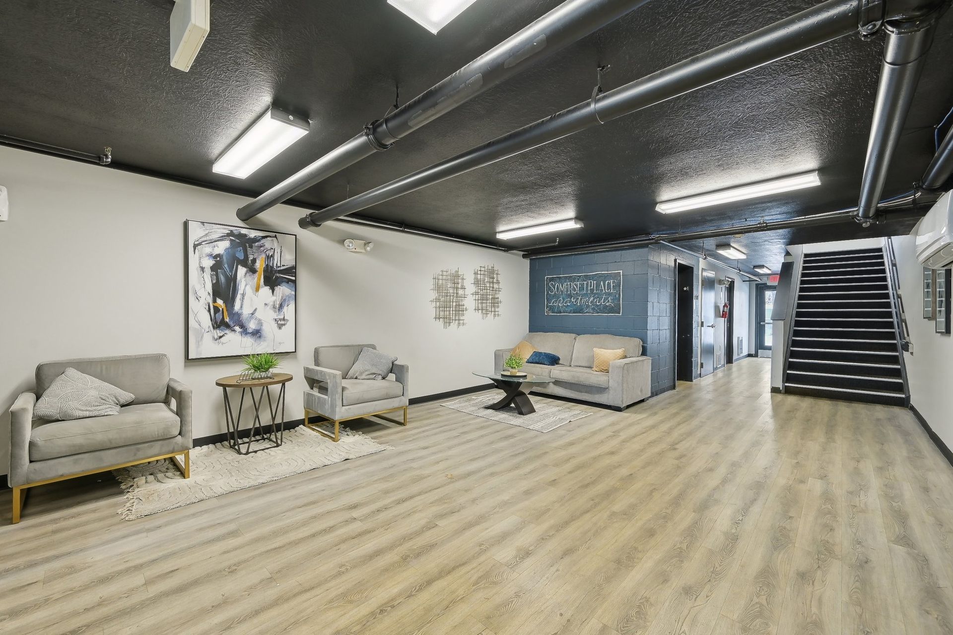 A living room with a couch , chairs , and stairs.