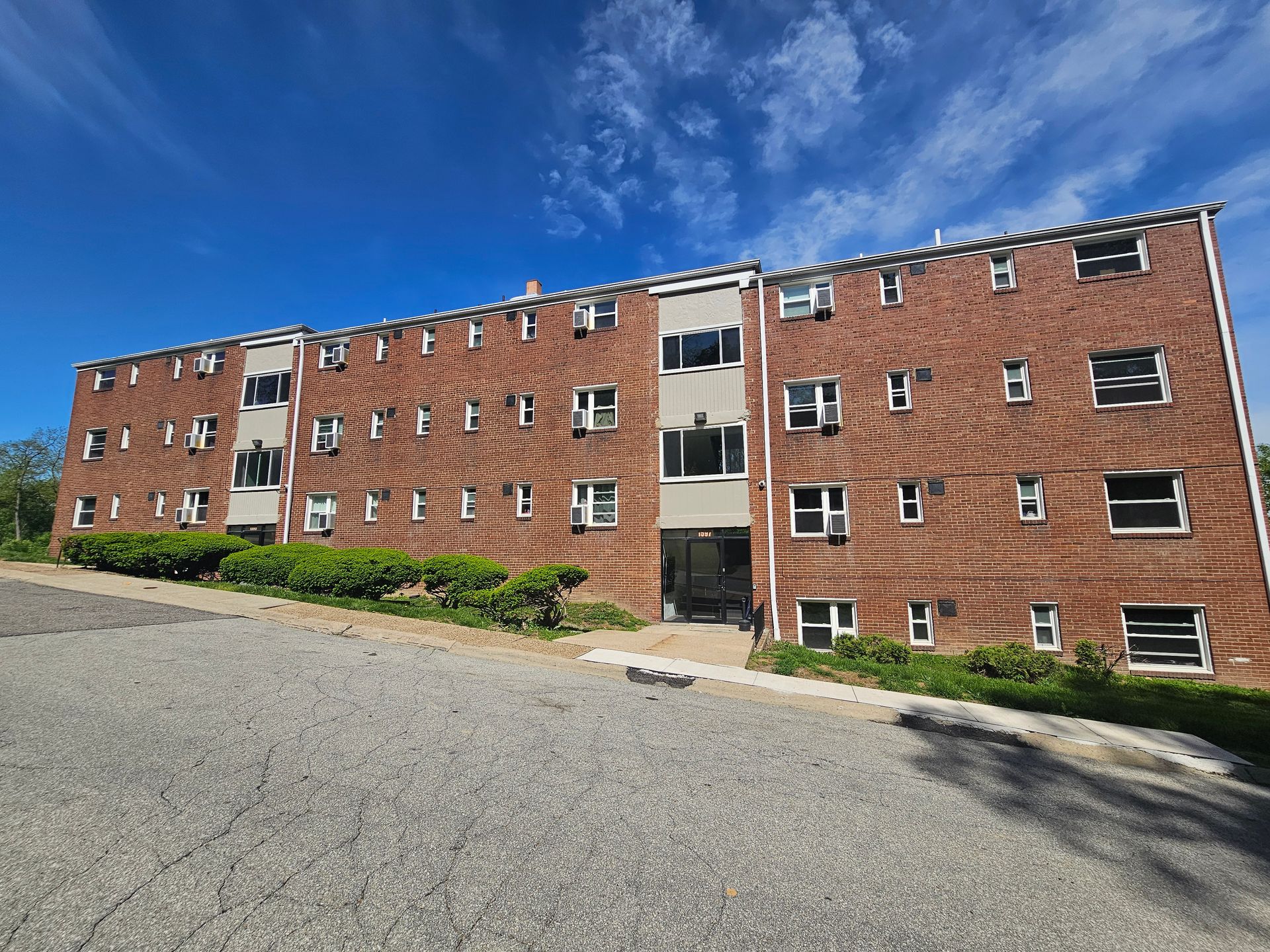 A large brick building with a lot of windows is sitting on top of a hill.