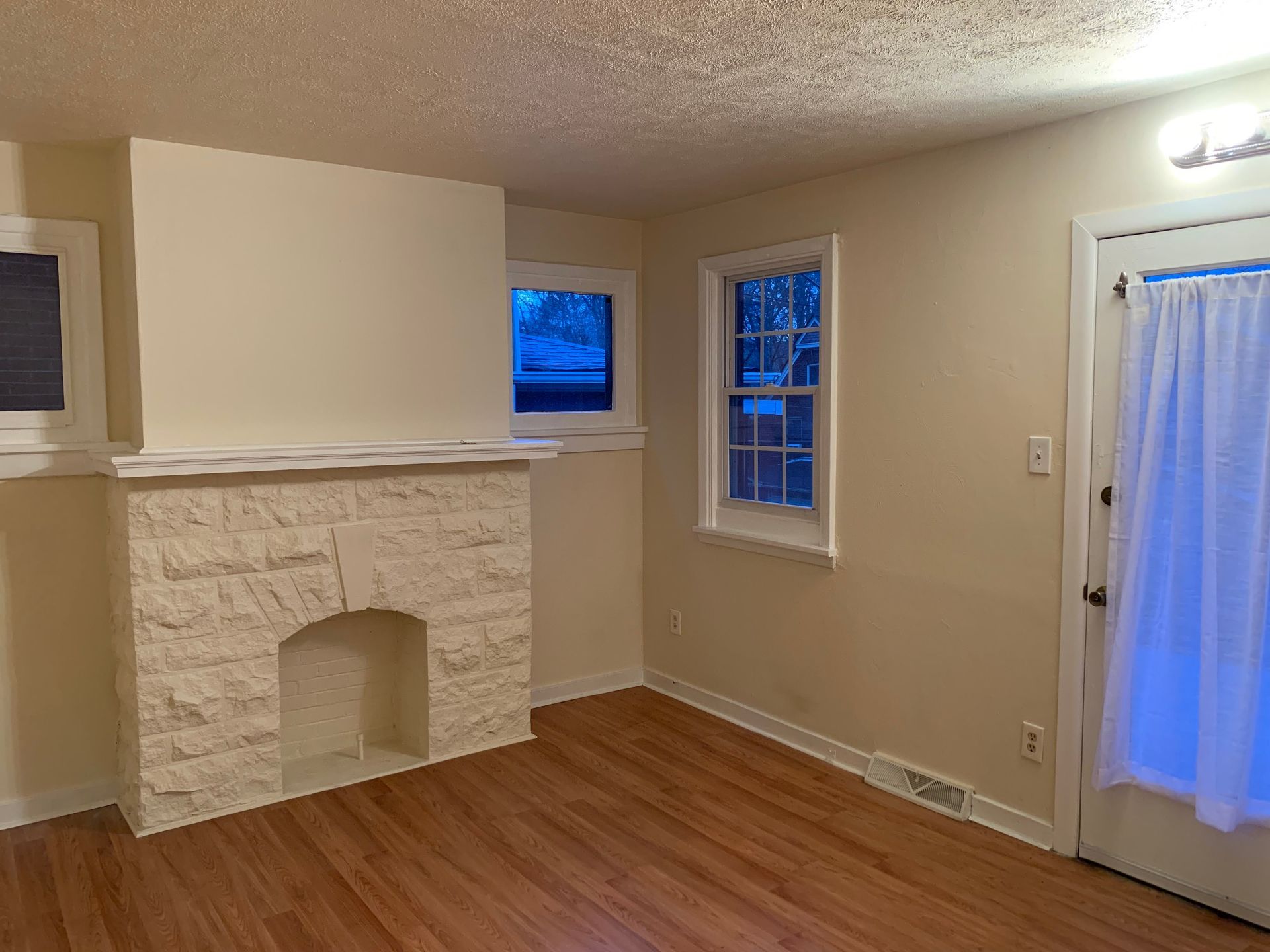 An empty living room with a fireplace and a window.