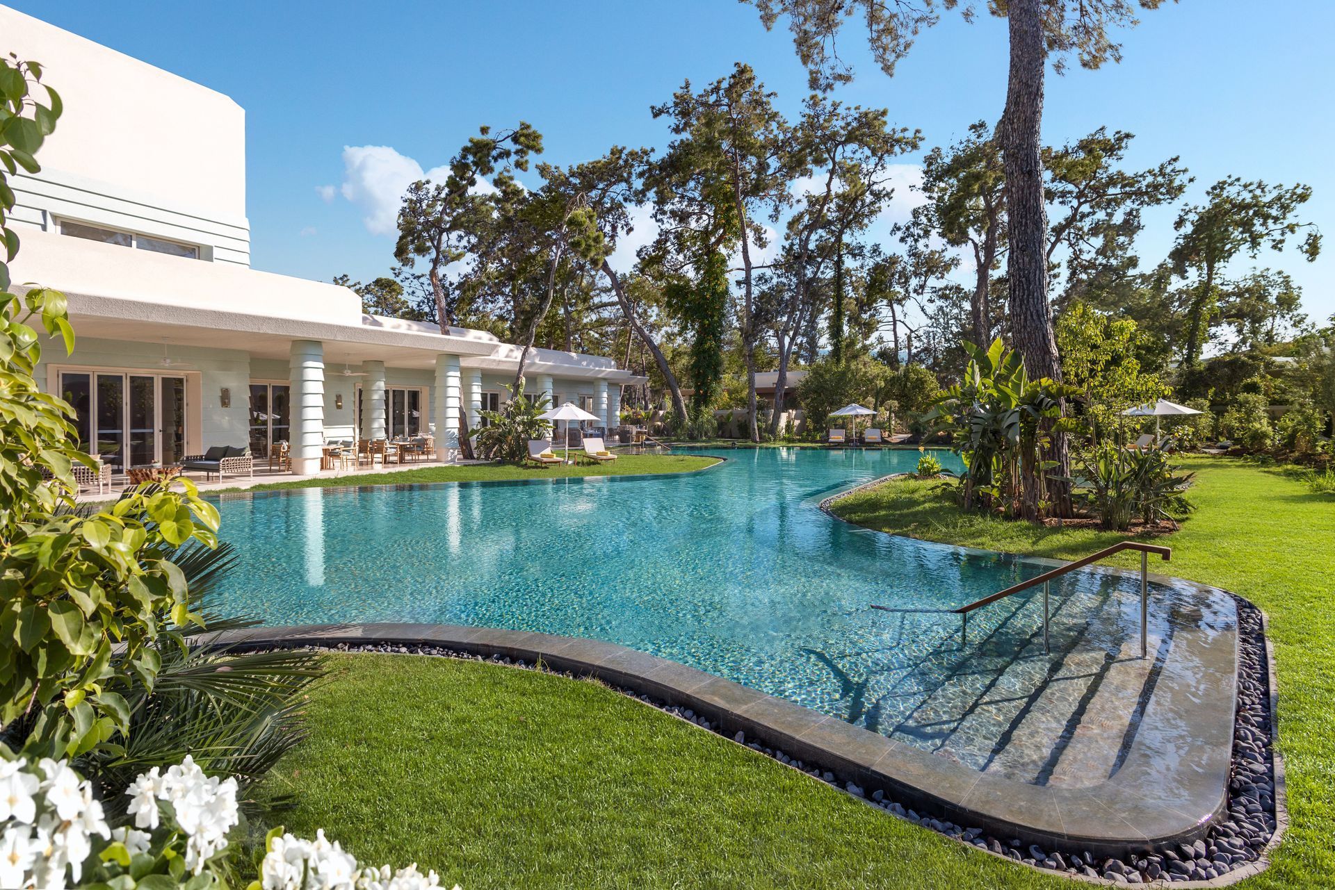 There is a large swimming pool in the middle of a lush green field.