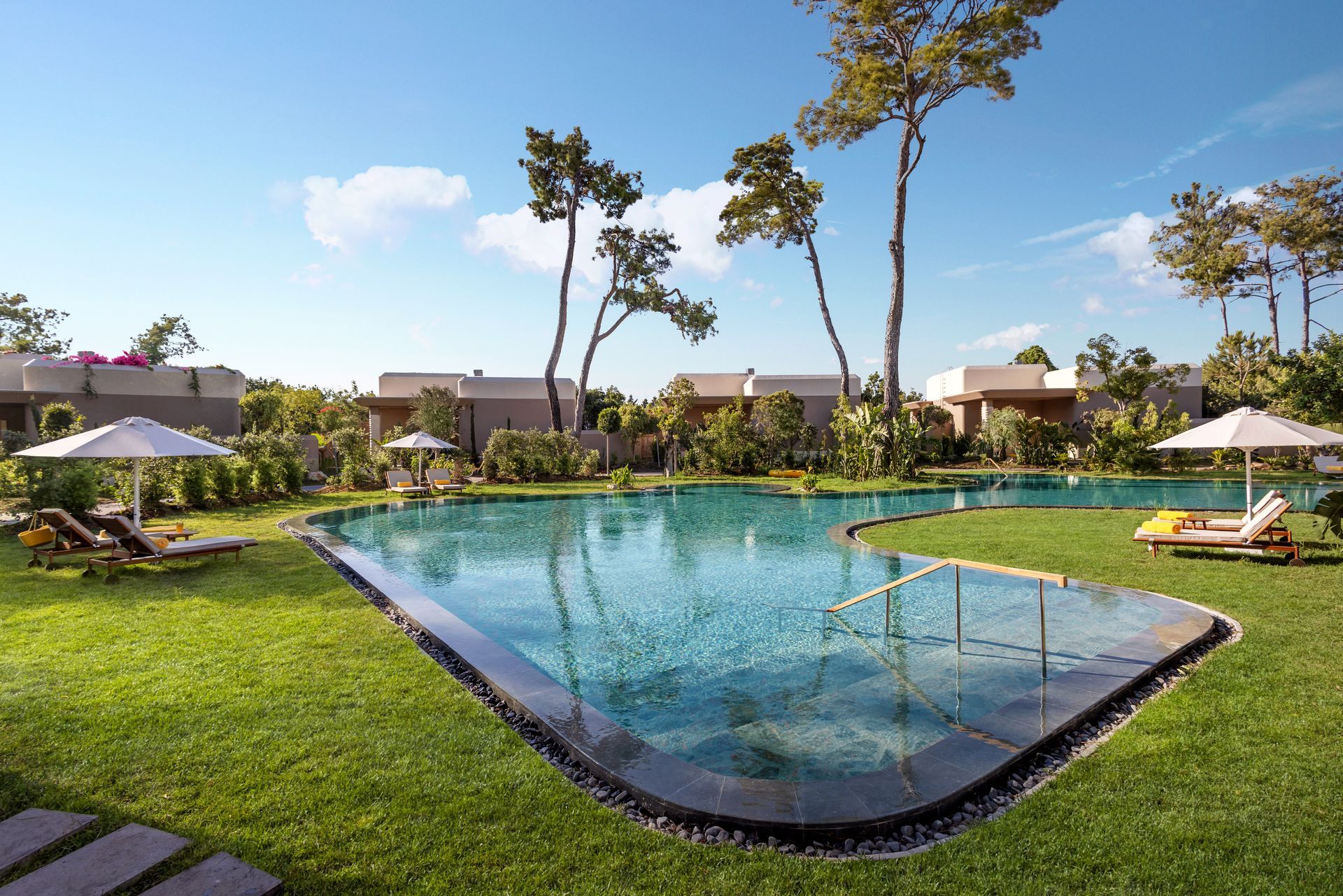 There is a large swimming pool in the middle of a lush green field.