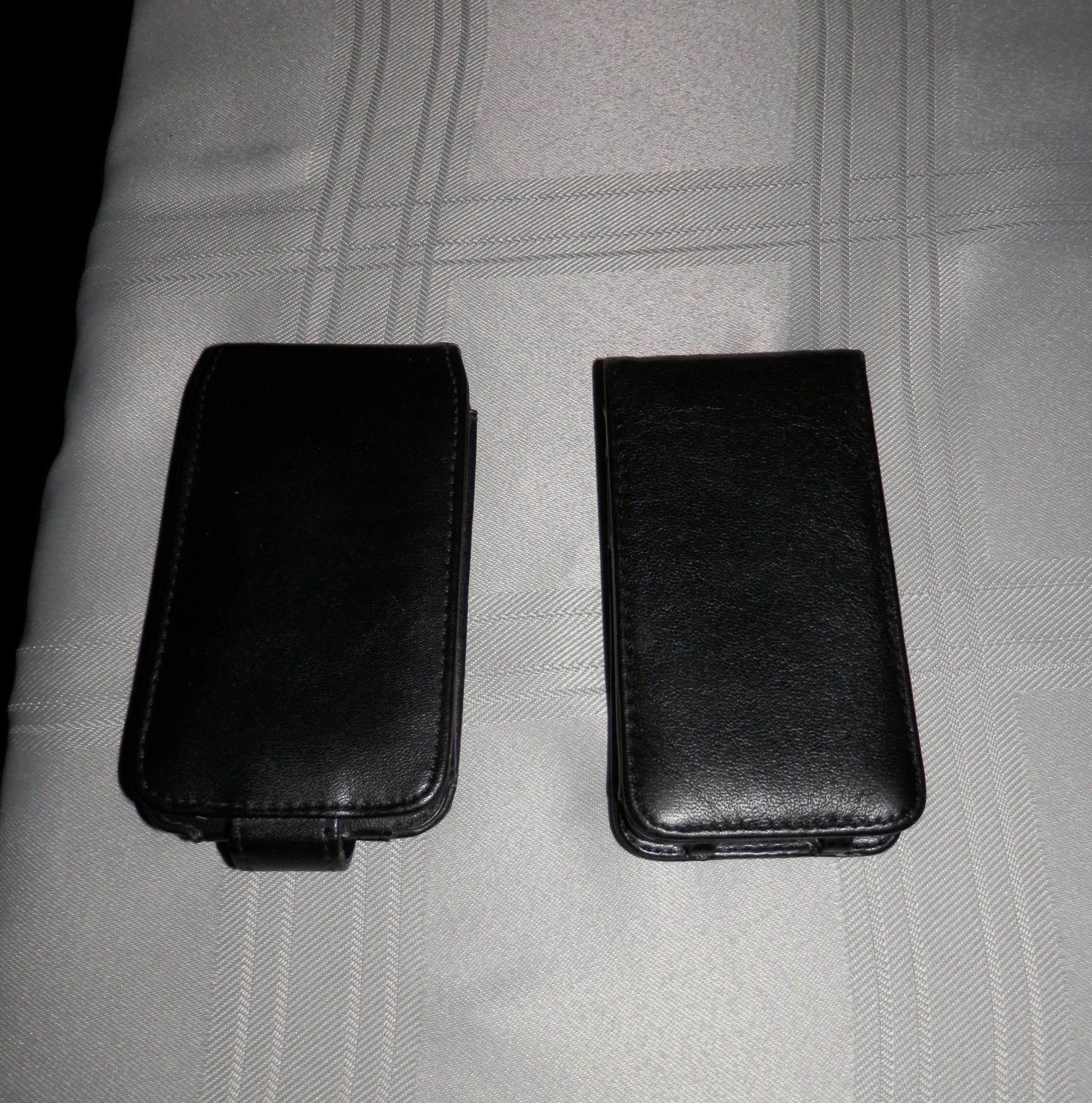 Two black leather cases are sitting on a white table cloth.