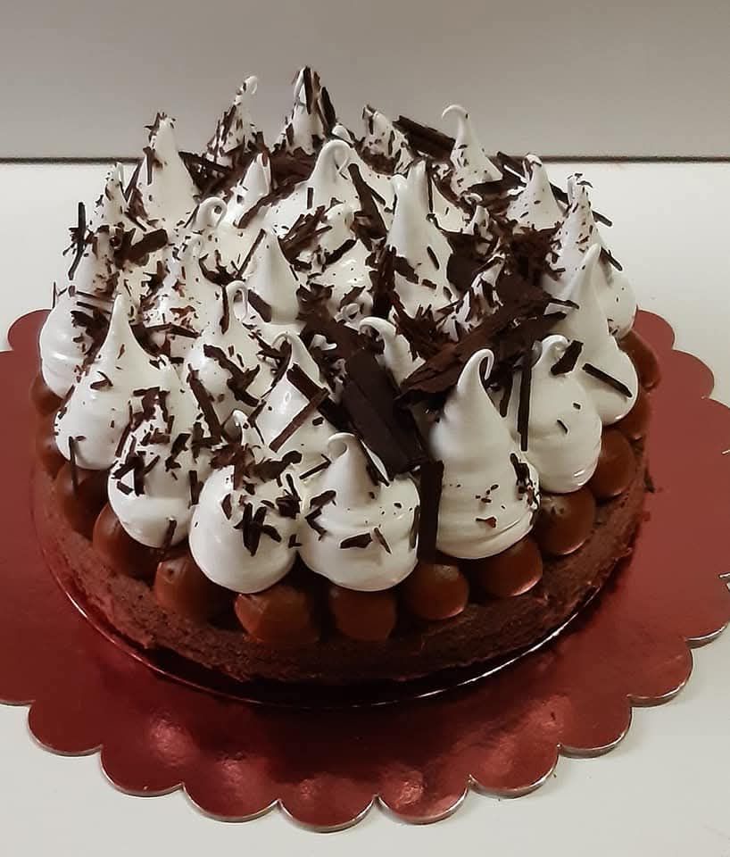 Pastel de crema con cobertura de chocolate sobre una fuente roja con borde festoneado.