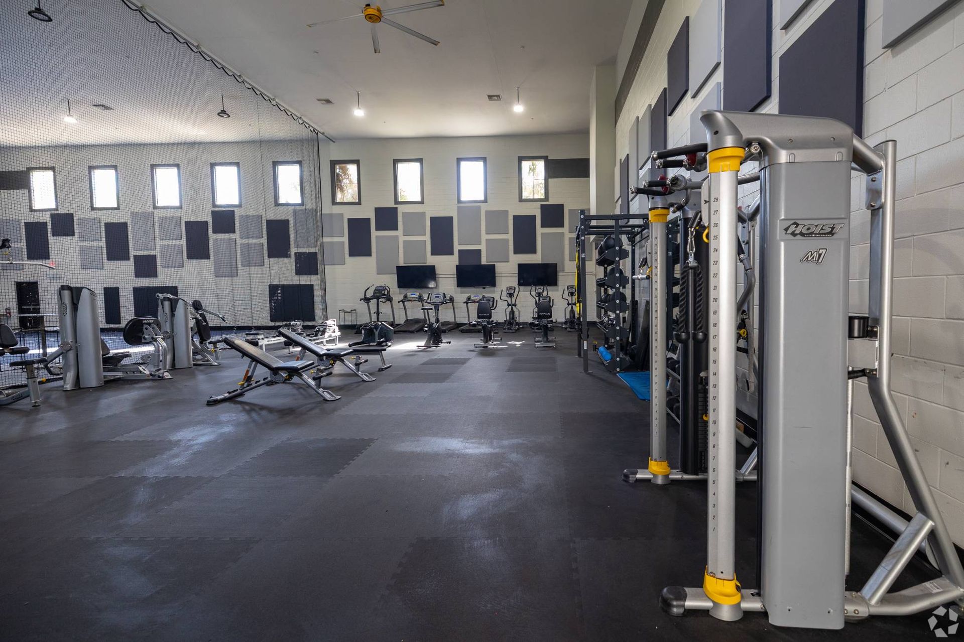 Indoor gym with cardio machines, free weights, and weight machines.