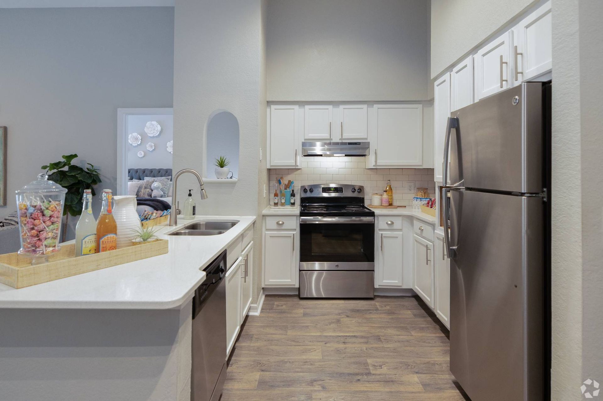 Bright kitchen in an apartment with white cabinets, stainless-steel appliances, island sink.