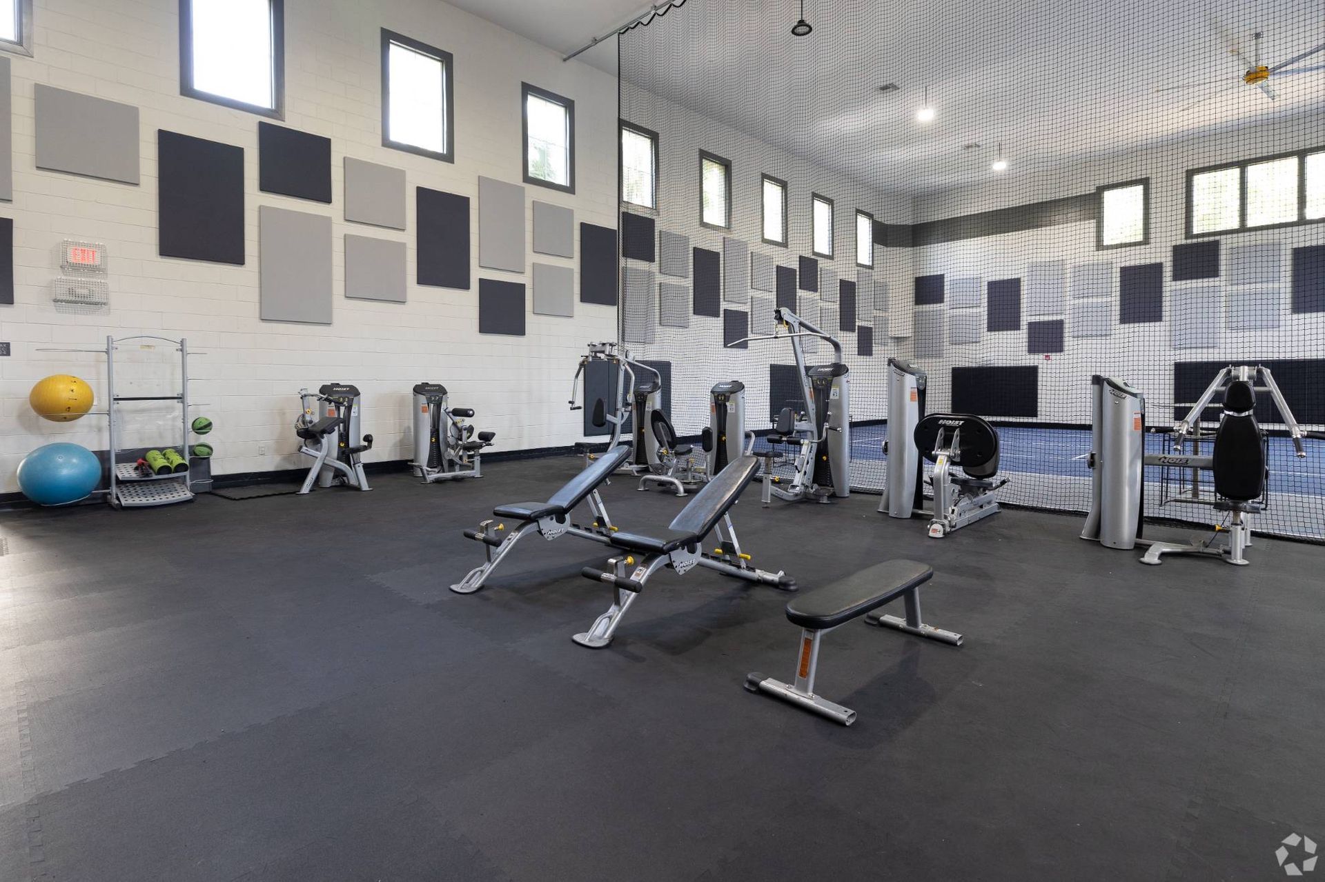Indoor apartment gym with benches, weight machines, and cardio equipment.