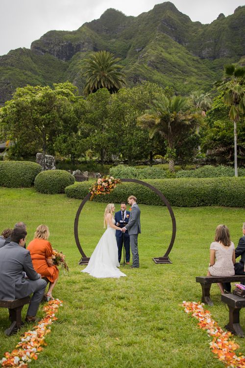 A Bride And Groom Are Getting Married In A Field With Mountains In The Background - Honolulu, HI - Bella Rosa Corporation