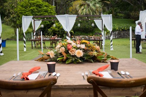 A Wooden Table With Two Chairs And A Vase Of Flowers On It - Honolulu, HI - Bella Rosa Corporation