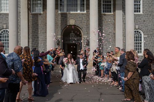 A Bride And Groom Are Being Showered With Confetti Outside Of A Building - Honolulu, HI - Bella Rosa Corporation