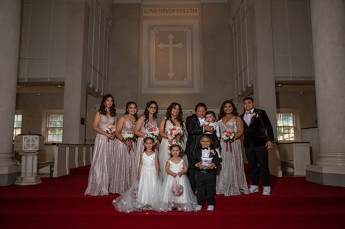 A Bride And Groom Are Posing For A Picture With Their Wedding Party In A Church - Honolulu, HI - Bella Rosa Corporation