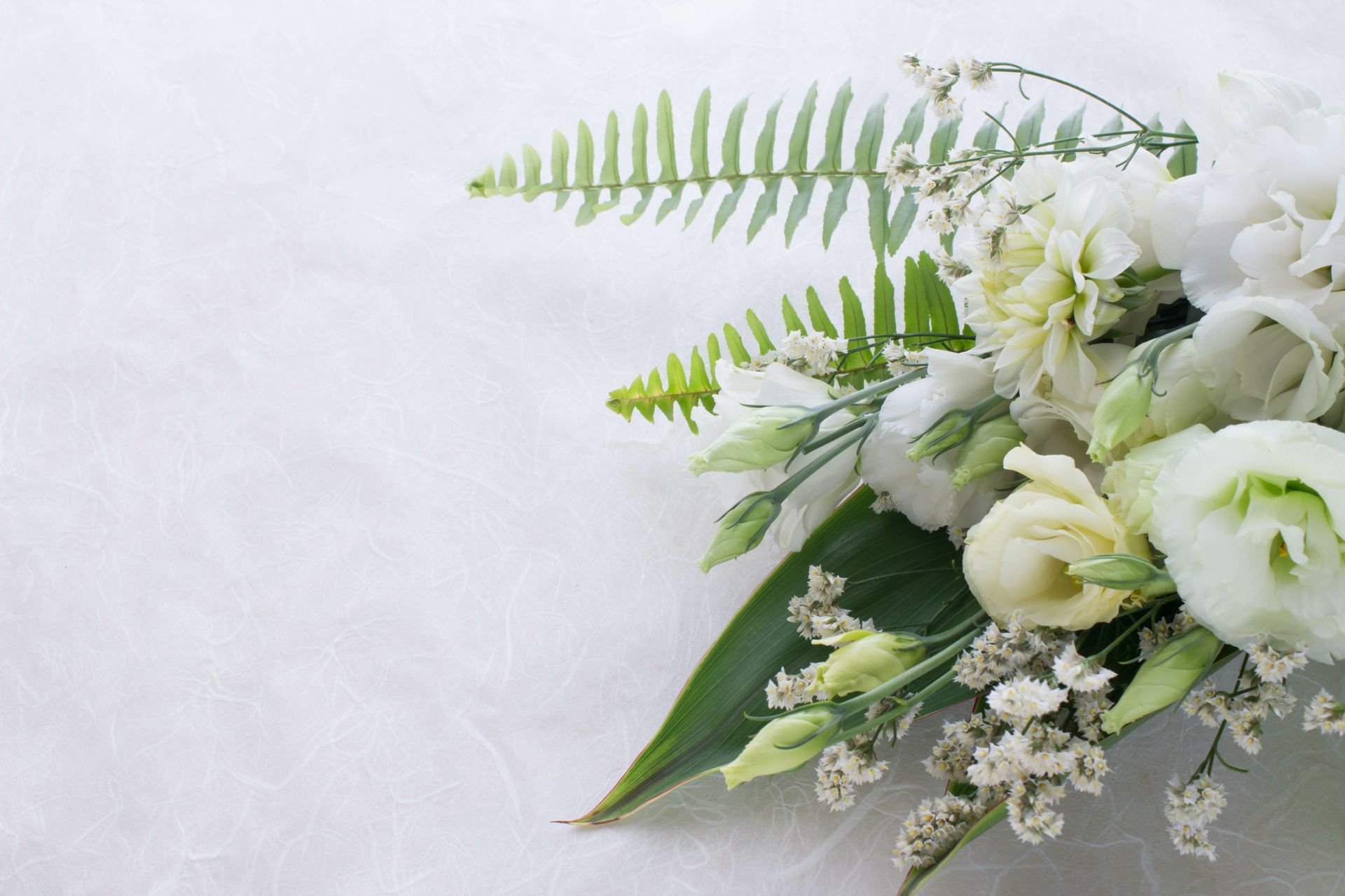 Flower arrangement of several kinds of white flowers and leaves.