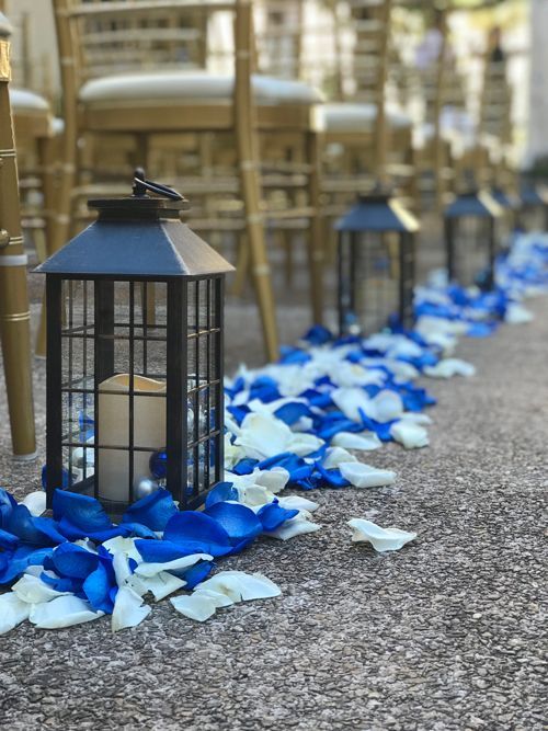 A Row Of Lanterns Sitting On Top Of A Carpet Covered In Blue And White Petals - Honolulu, HI - Bella Rosa Corporation