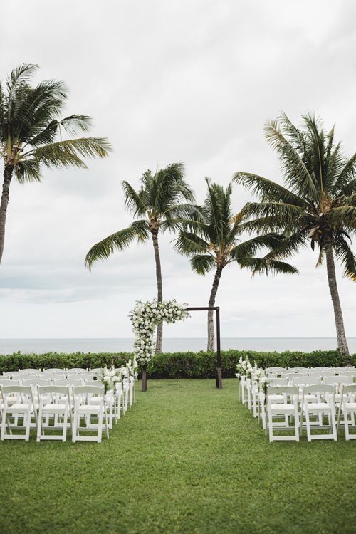 A Wedding Ceremony Is Taking Place In A Lush Green Field With Palm Trees In The Background - Honolulu, HI - Bella Rosa Corporation