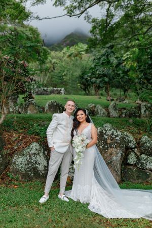A Bride And Groom Are Posing For A Picture In Front Of A Mountain - Honolulu, HI - Bella Rosa Corporation