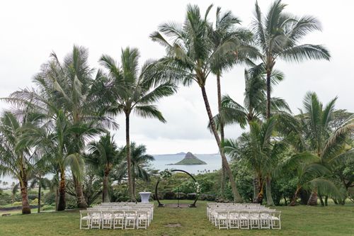 A Wedding Ceremony Is Taking Place In The Middle Of A Lush Green Field Surrounded By Palm Trees - Honolulu, HI - Bella Rosa Corporation