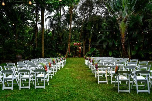 A Row Of White Folding Chairs Are Lined Up In A Lush Green Field - Honolulu, HI - Bella Rosa Corporation