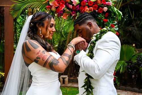 A Bride And Groom Are Kissing Each Other's Hands During Their Wedding Ceremony - Honolulu, HI - Bella Rosa Corporation