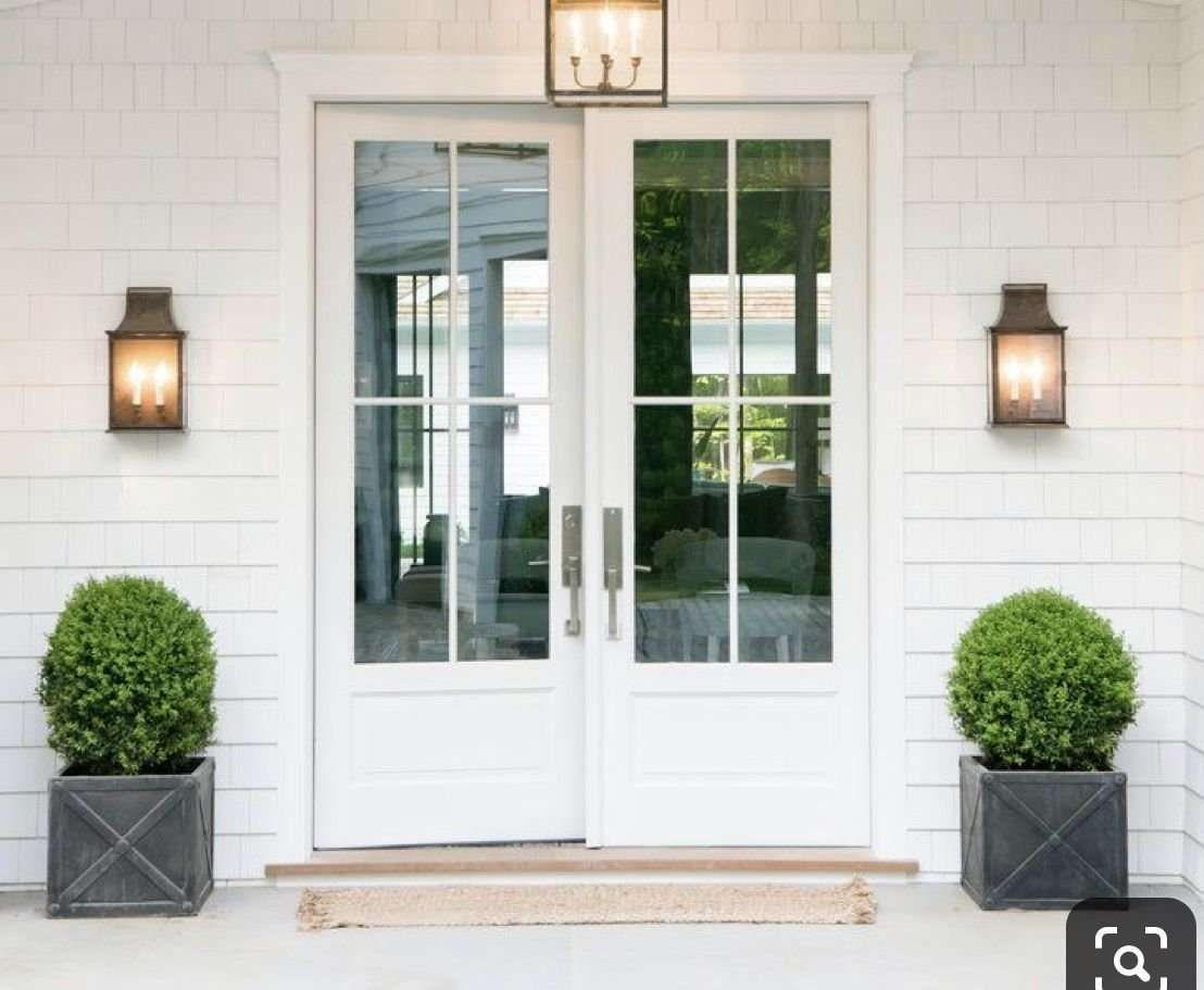 A white house with a white door and two potted plants in front of it