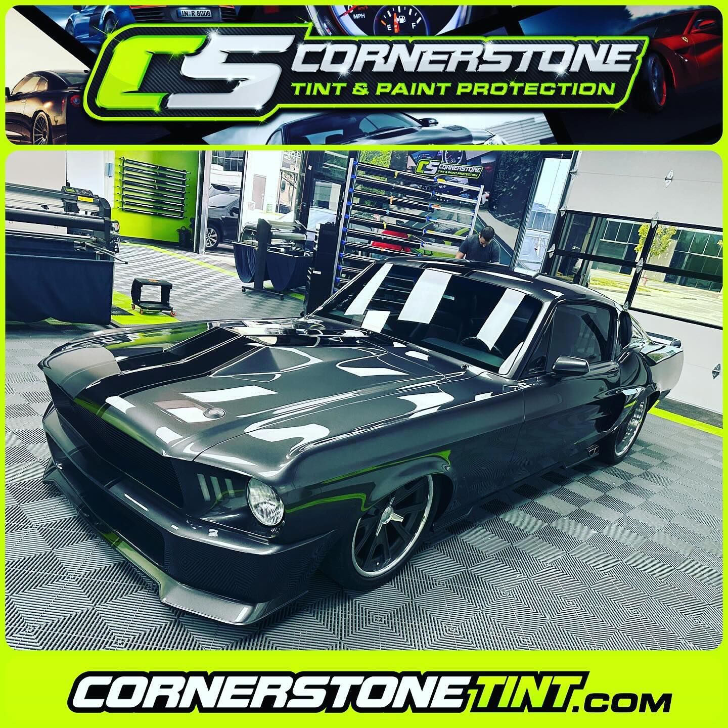 A black mustang is parked in a cornerstone tint and paint protection shop.