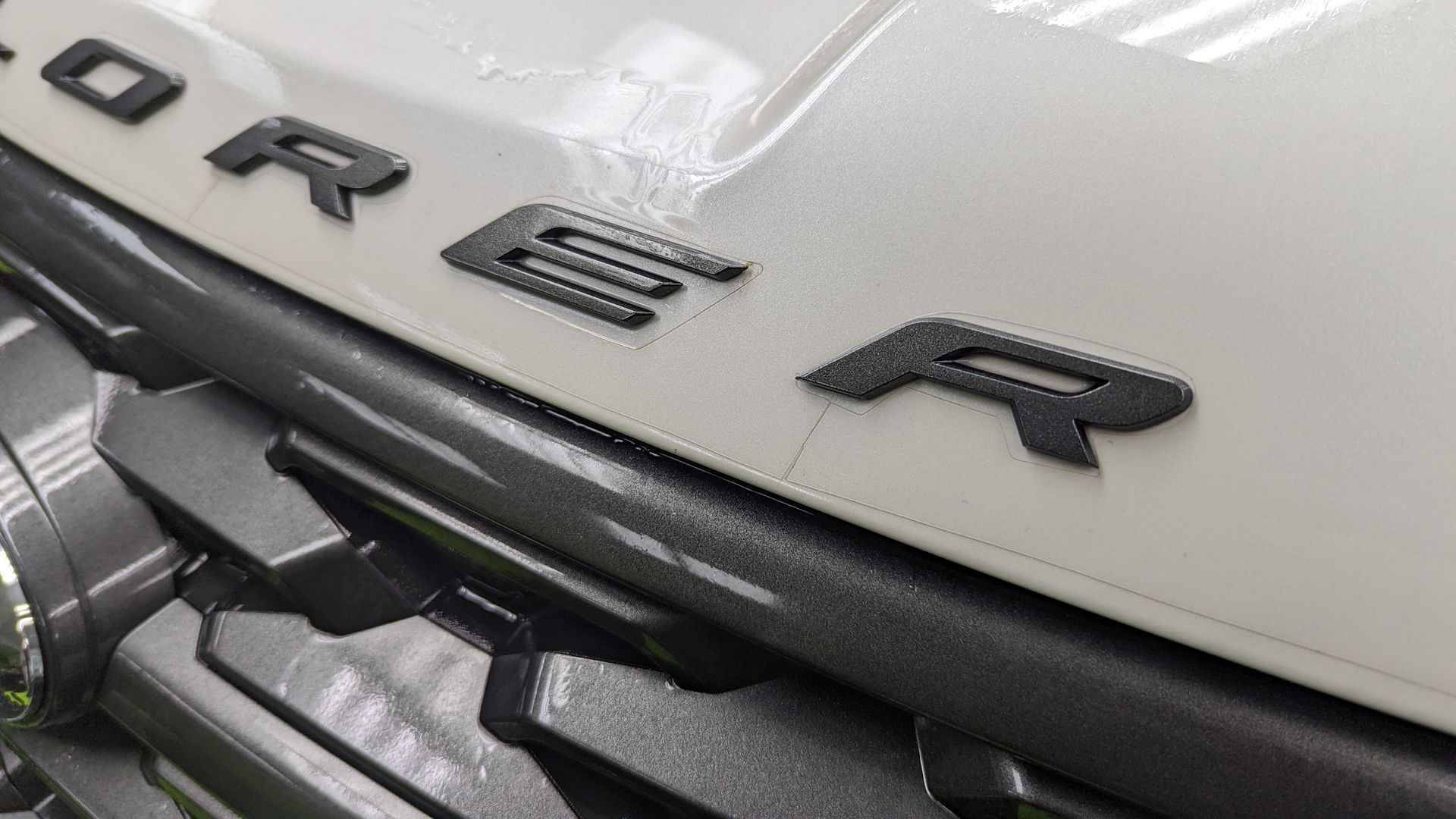 A close up of the front grille of a white range rover.