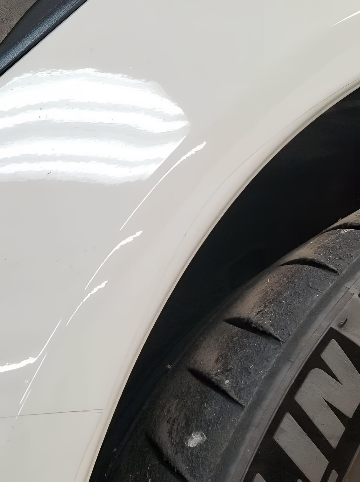 A close up of a white car with a michelin tire