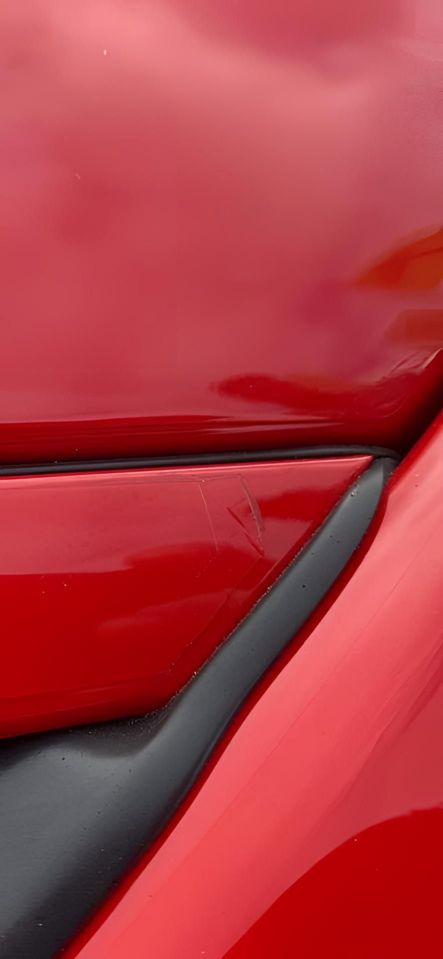 A close up of the hood of a red car with a black trim.