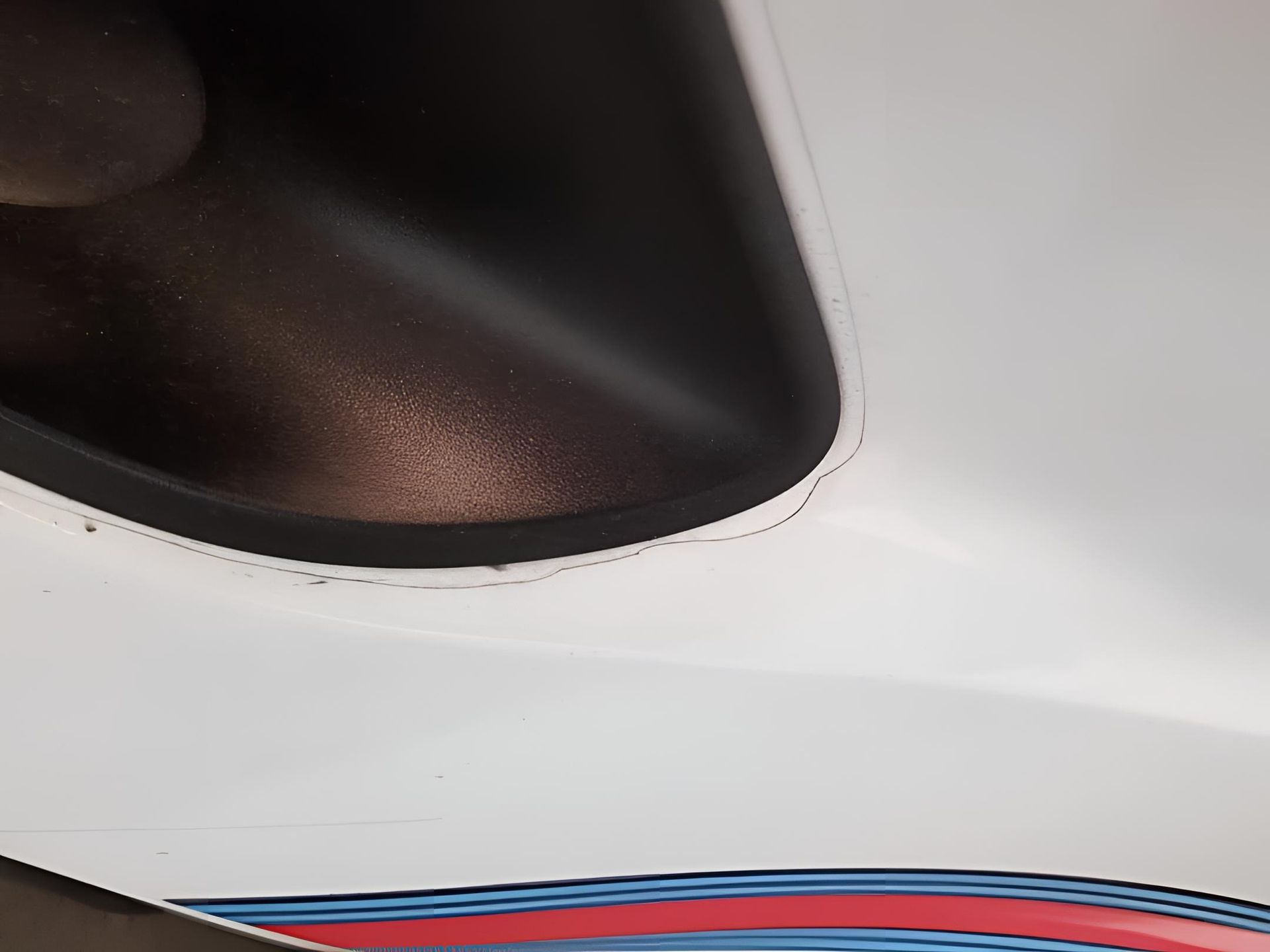 Close-up of a white car with black trim and a blue and red stripe.