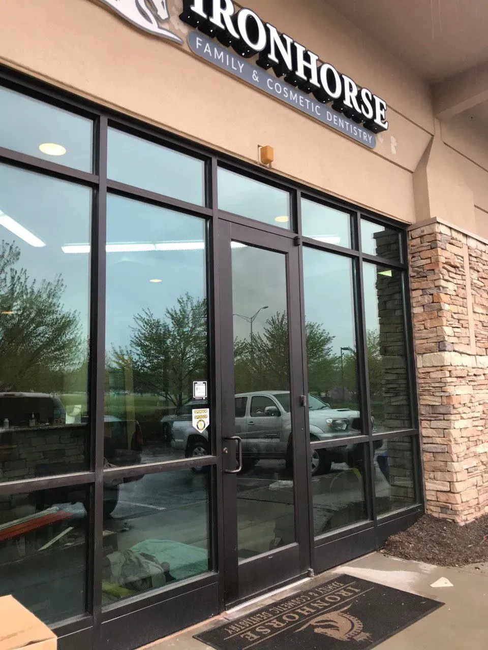 Exterior of Ironhorse Family & Cosmetic Dentistry, glass windows and door, beige building.