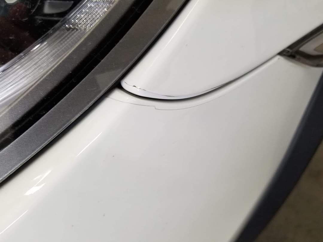 A close up of a white car 's bumper and headlight.