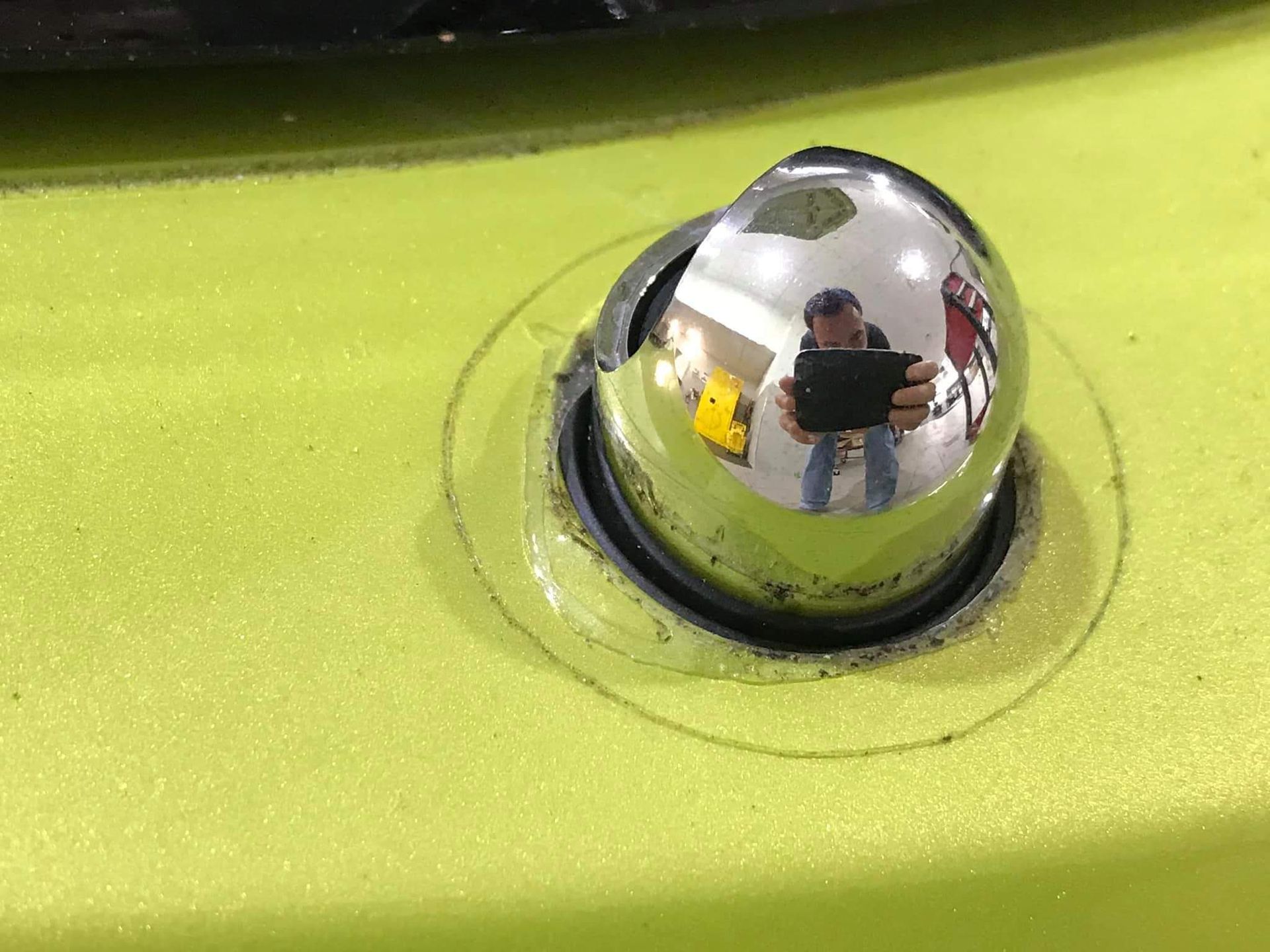 A man is taking a picture of himself in a mirror on the side of a car.