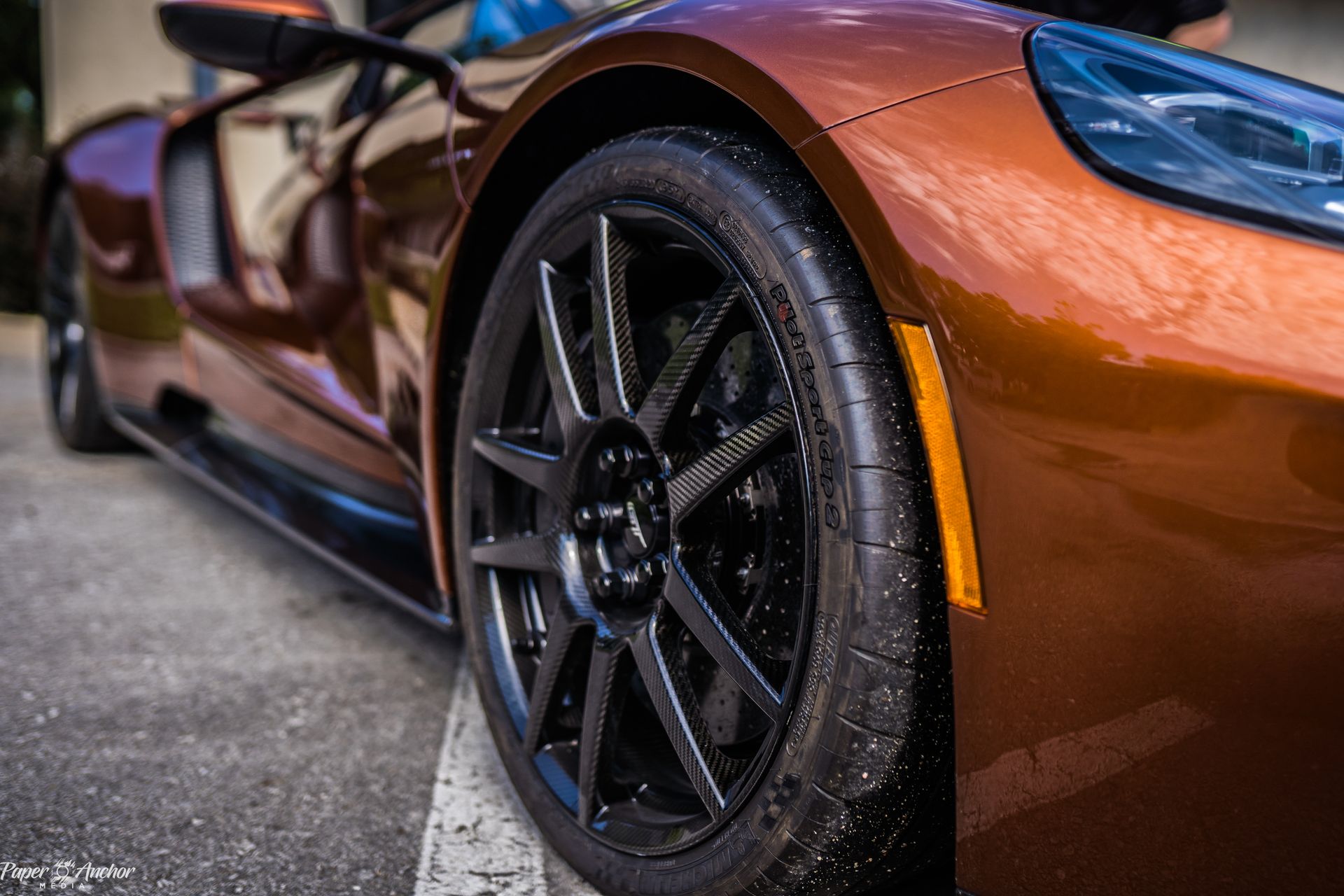 A close up of the front wheel of a brown sports car.