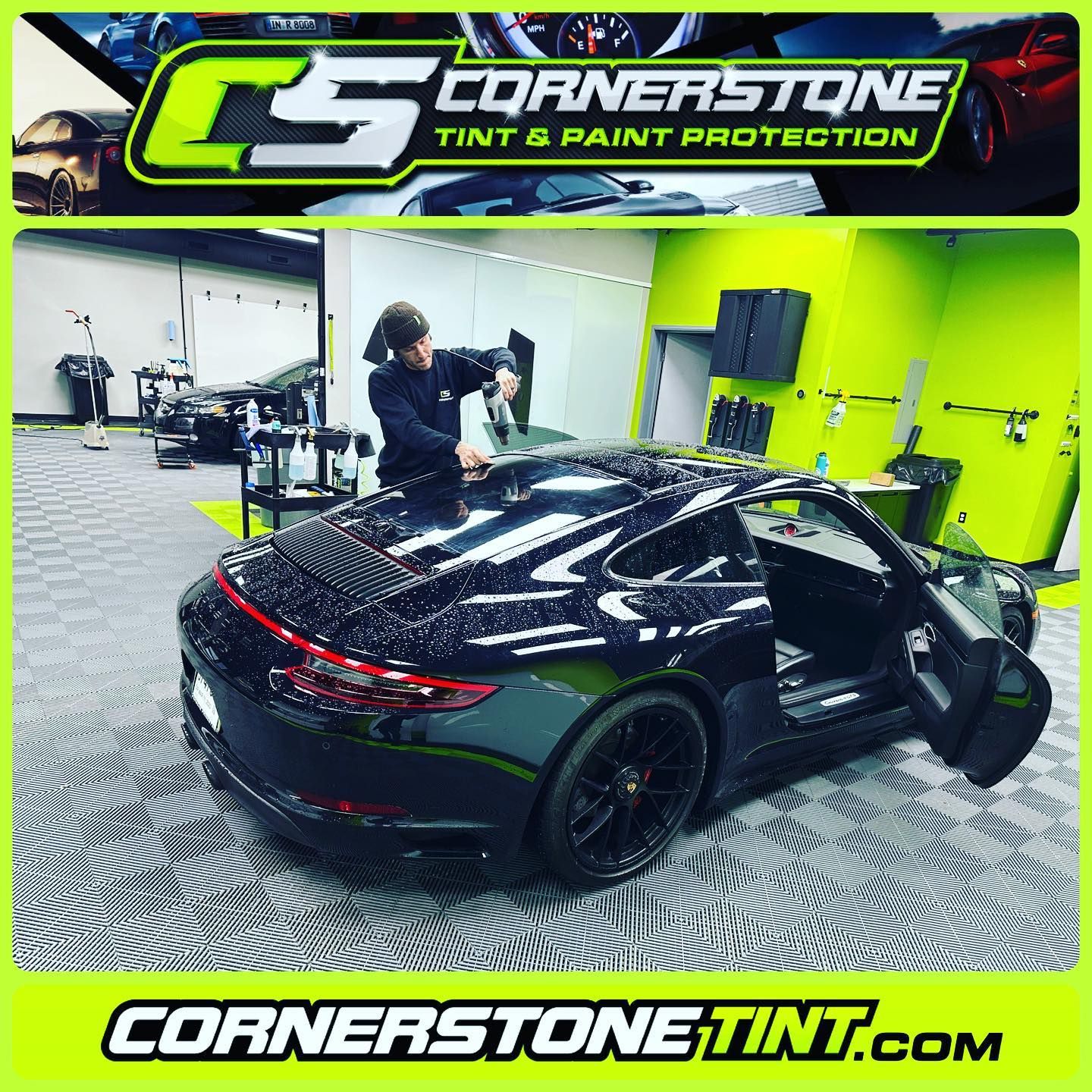 A black car is being tinted by a man in a garage.