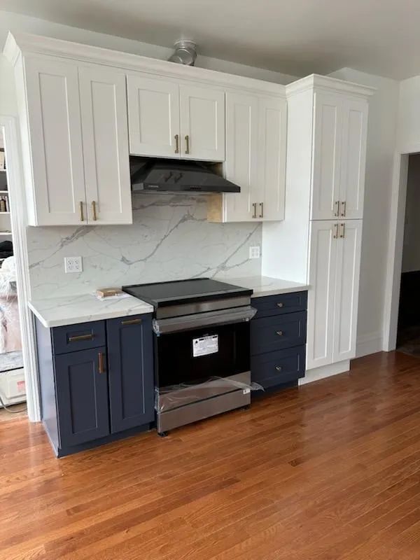 A kitchen with white cabinets and blue drawers and a stove.